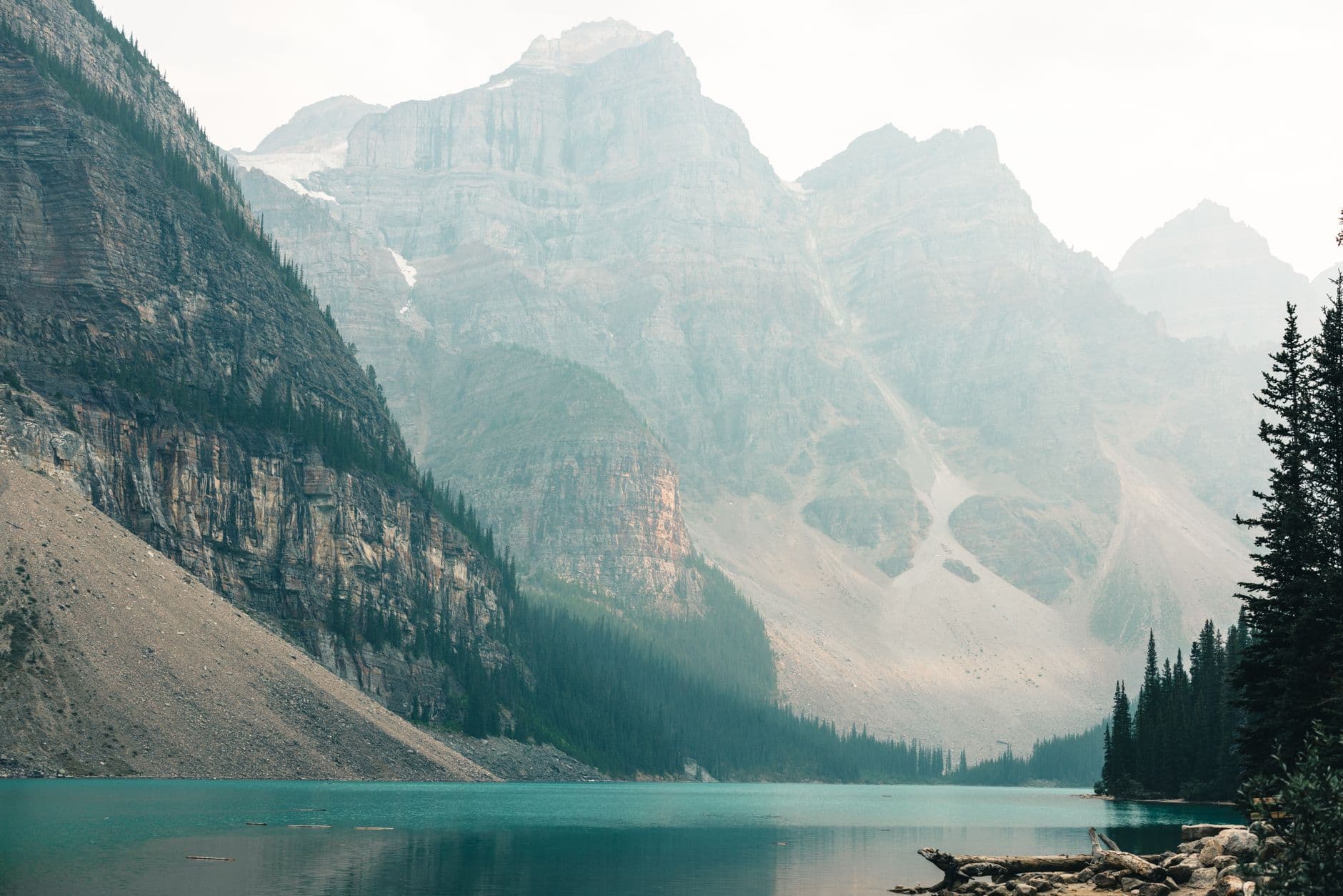 A turquoise glacial lake nestled in a dramatic mountain valley with coniferous forests and steep rocky peaks in the Canadian Rockies. - Photo by Ali Kazal on Pexels