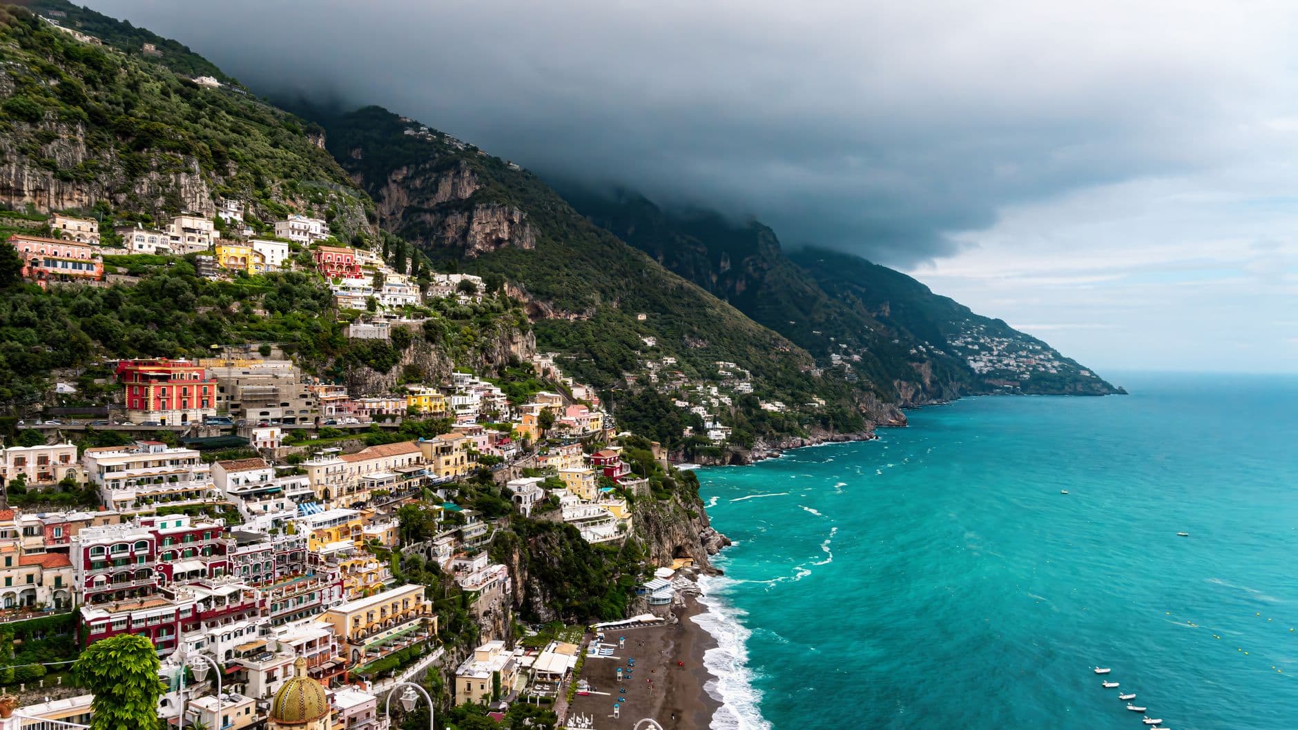 A panoramic view of Positano village on the Amalfi Coast, showing densely packed colorful buildings built vertically into dramatic limestone cliffs above turquoise Mediterranean waters. - Photo by Alain Garcia on Pexels
