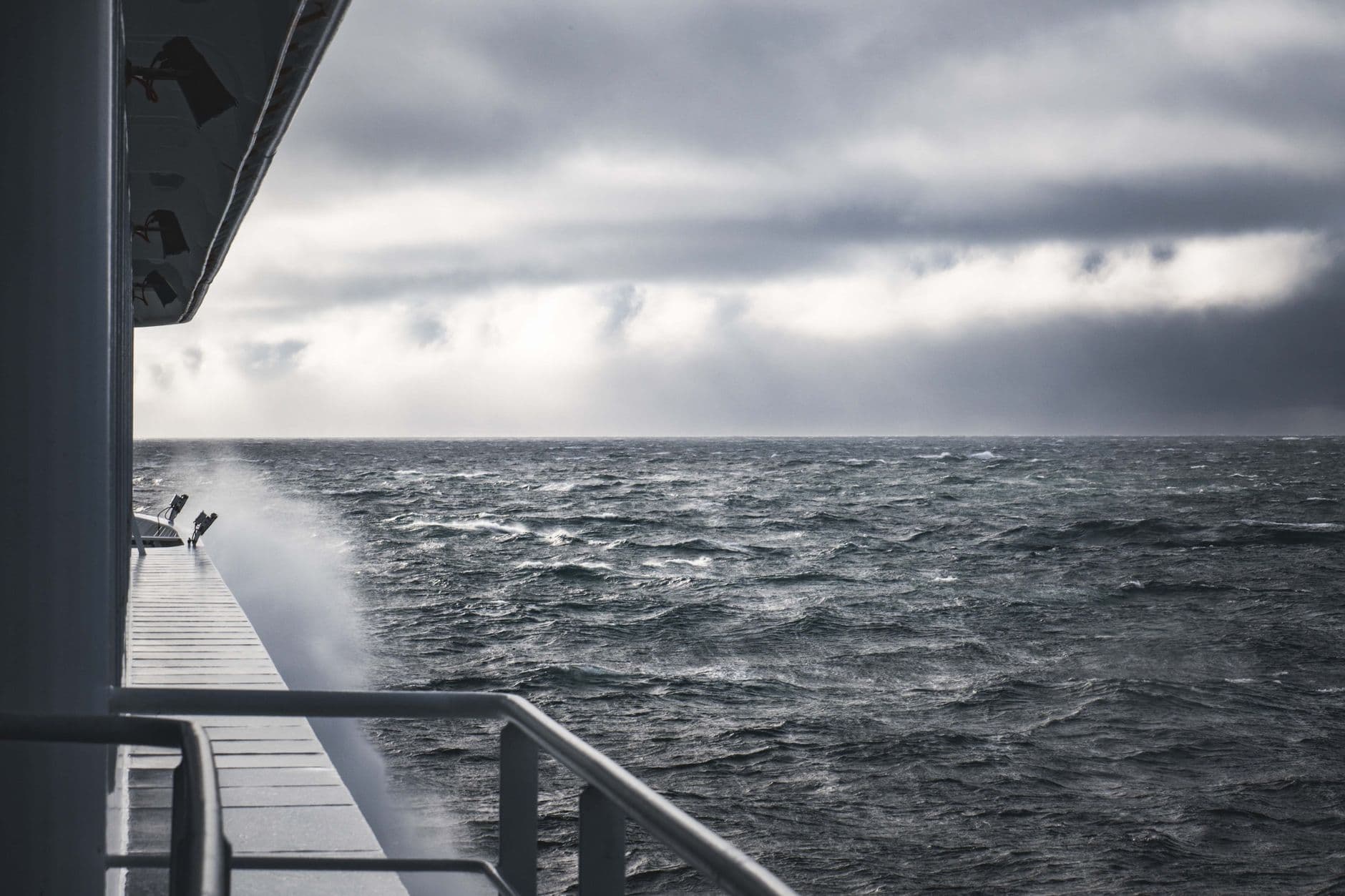 A view from a ship's deck during rough seas, showing the vessel's railing and superstructure against dark, churning ocean waters under an overcast sky. - Photo by Francesco Ungaro on Pexels