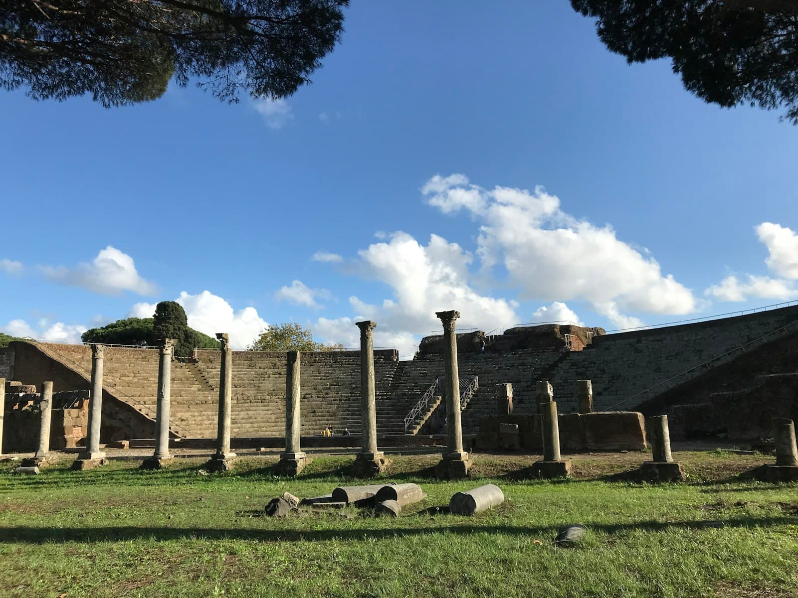 Ruins of a Roman structure with Corinthian columns, stone walls, and a grass courtyard, typical of the Ostia Antica archaeological site near Rome. - Photo by Sayaka Ganz on Unsplash