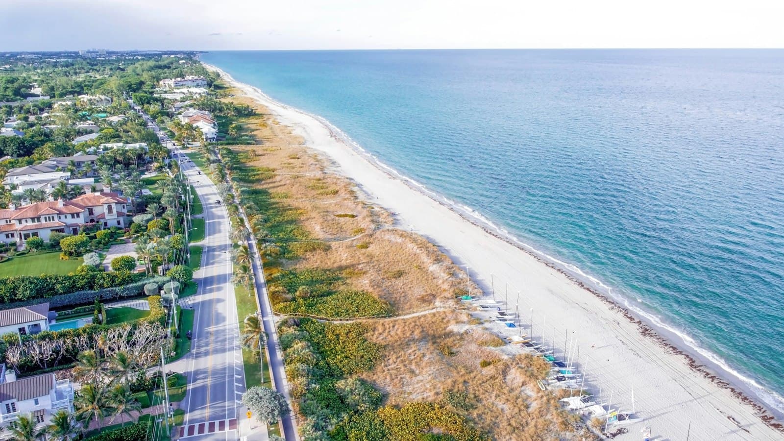 Aerial view of a developed beachfront community along a white-sand Gulf Coast beach, showing upscale residential properties, a pristine beach, and shallow turquoise waters. - Photo by Lesia on Unsplash