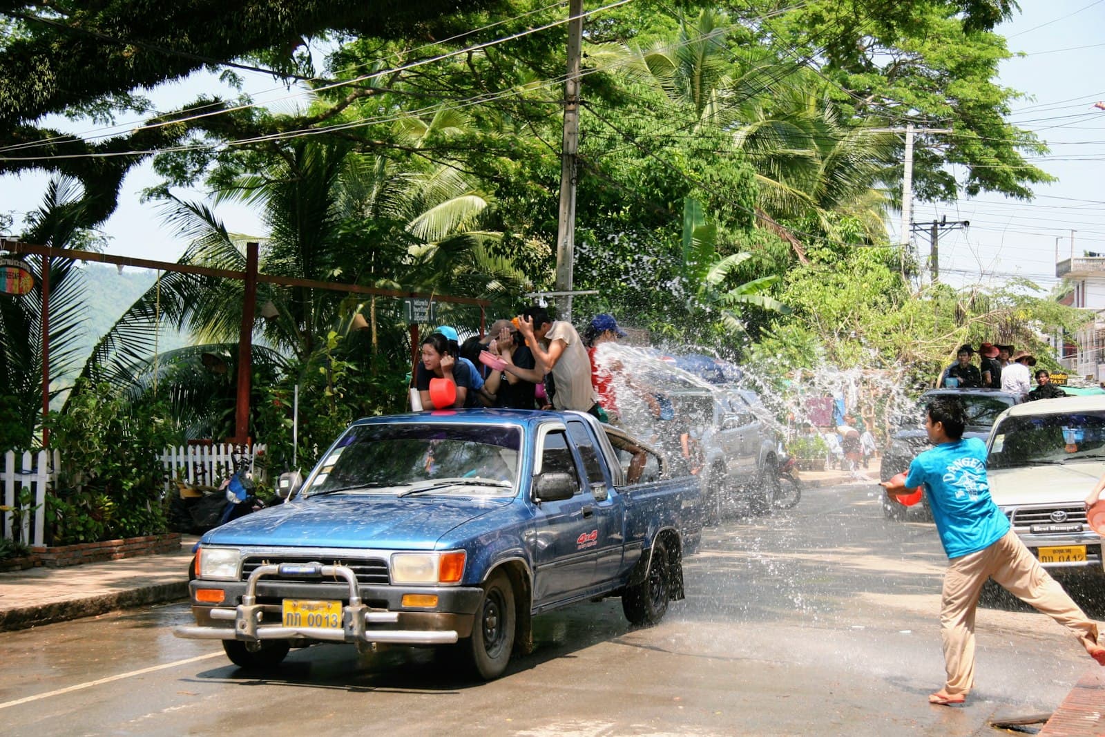 A Songkran water festival celebration on a street in Laos, with people in a pickup truck spraying water at pedestrians during the Pi Mai (Lao New Year) festival. - Photo by Long (lTiga) Nguyen on Unsplash