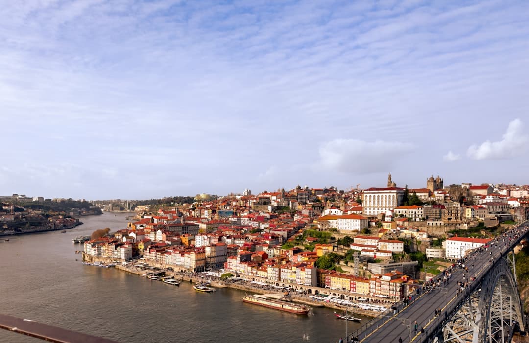 A panoramic view of Porto's historic Ribeira district rising steeply from the Douro River, with densely packed multicolored buildings, traditional Portuguese architecture, and the Dom Luís Bridge visible on the right. - Photo by Dorin Seremet on Unsplash