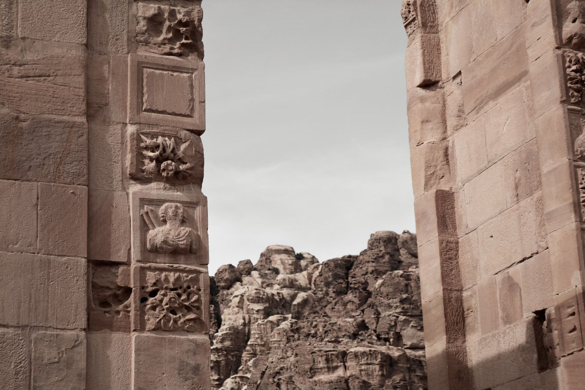 Detailed view of ornately carved stone pillars and decorative reliefs from an ancient Persian monumental gateway, showing Achaemenid sculptural elements framing a rocky landscape. - Photo by Mert Çelik on Pexels