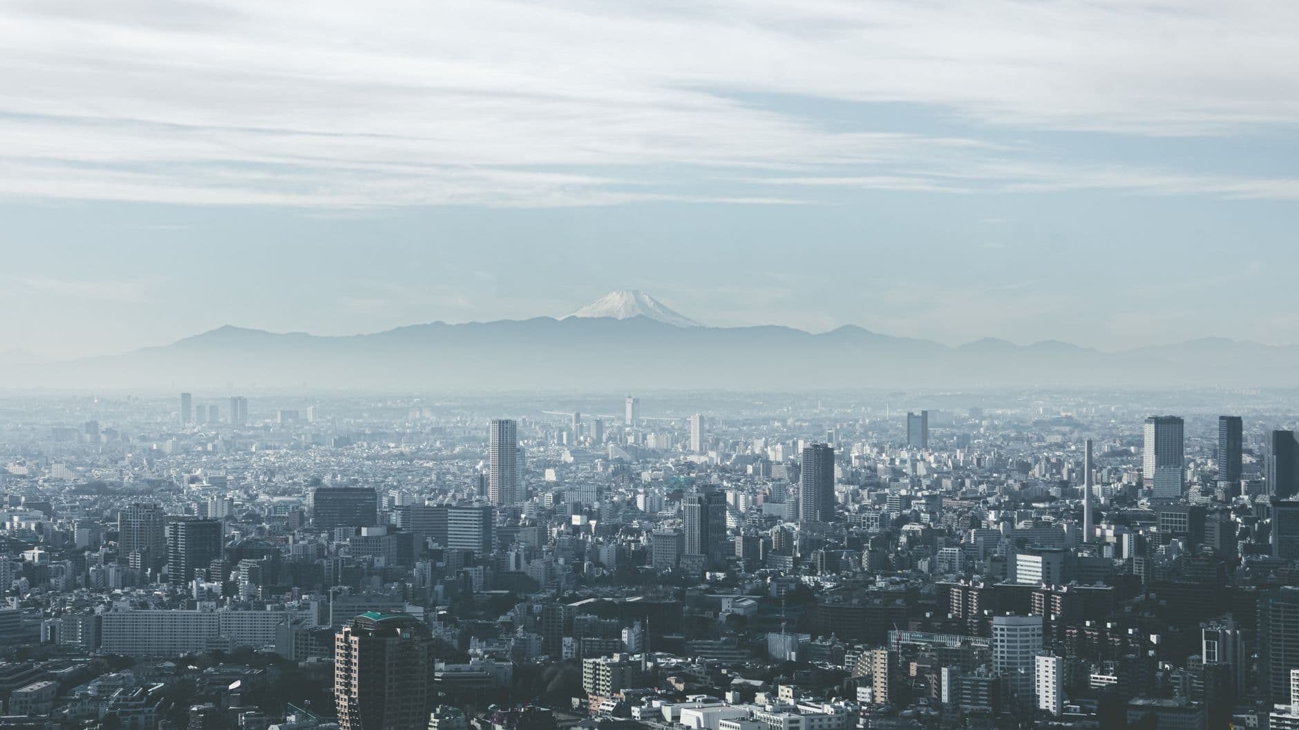 An aerial cityscape view of Tokyo with Mount Fuji visible on the horizon in the distance, showing the dense urban sprawl of Japan's capital. - Photo by Ruiz . on Pexels