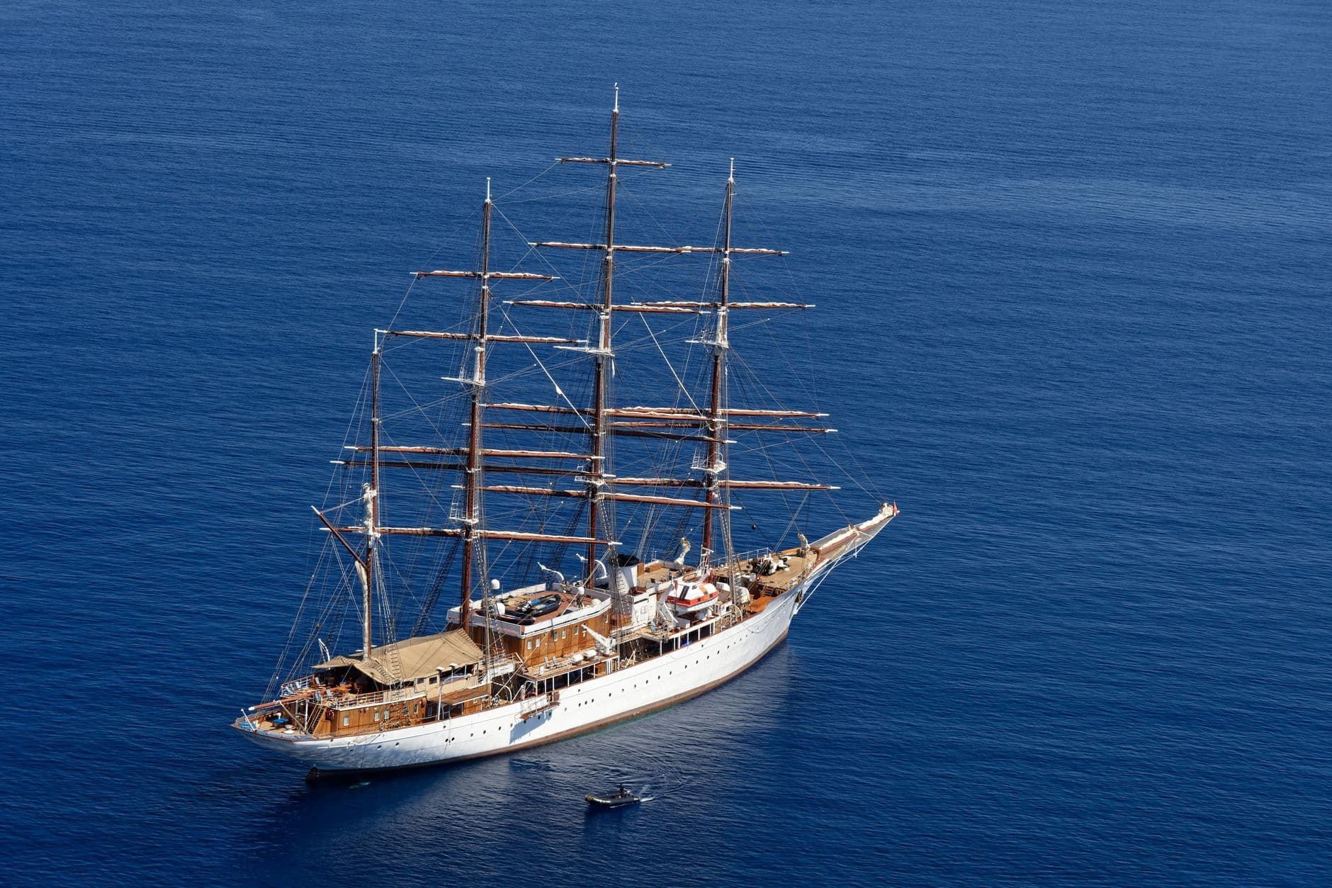 A full-rigged tall ship with white hull and wooden masts under full sail in deep blue ocean waters, photographed from above. - Photo by Gu Bra on Pexels