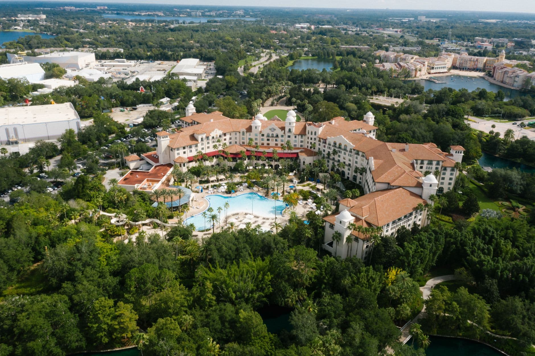 Aerial view of a large resort complex with Spanish/Mediterranean-style architecture, red-tile roofs, palm trees, and a lagoon-style pool, surrounded by dense subtropical forest and lakes characteristic of central Florida's theme-park resort corridor. - Photo by Mikhail Nilov on Pexels