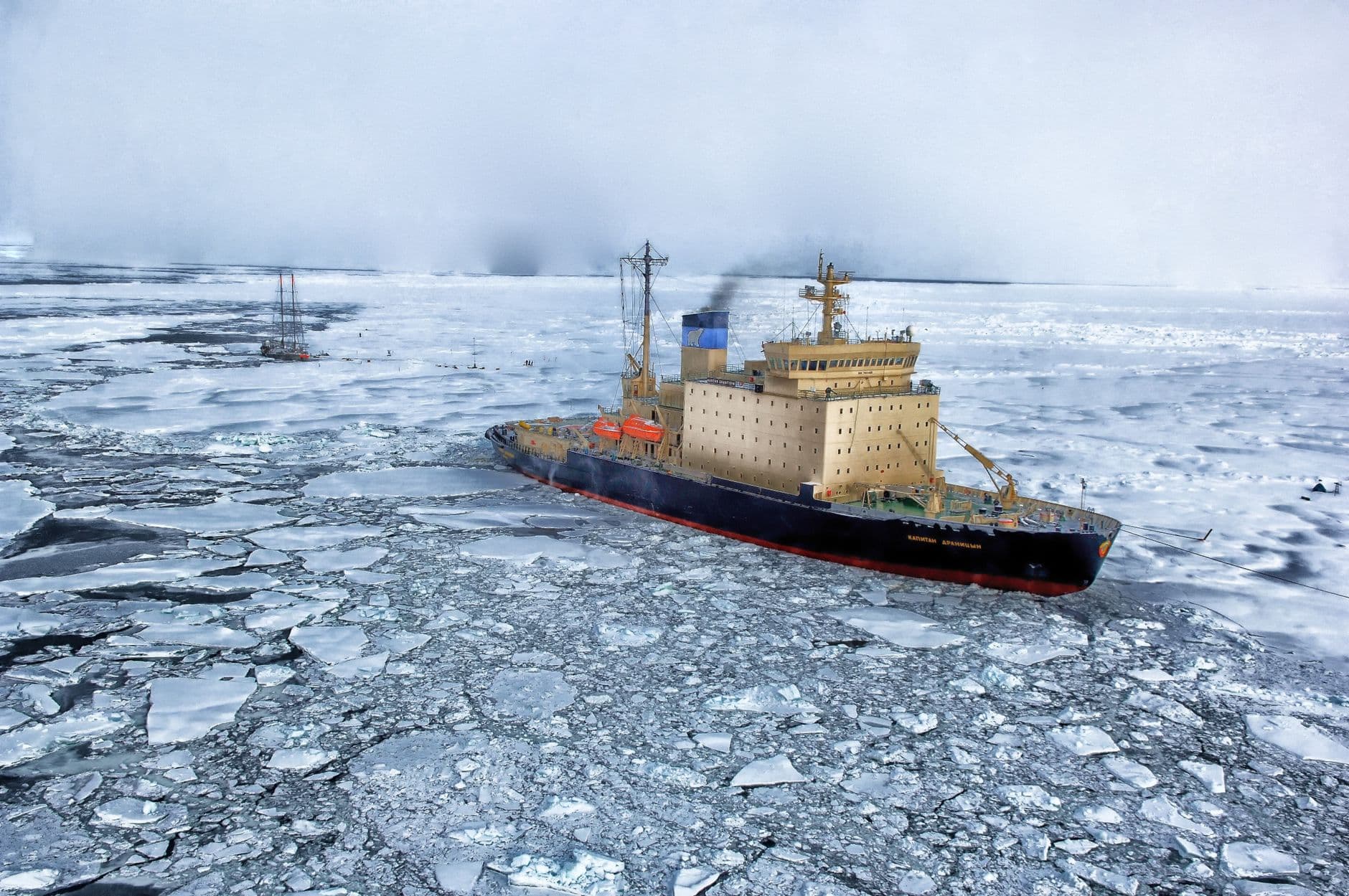 An icebreaker ship navigates through dense pack ice in the Weddell Sea, with support vessels visible in the background and heavy fog obscuring the distant horizon. - Photo by Pixabay on Pexels