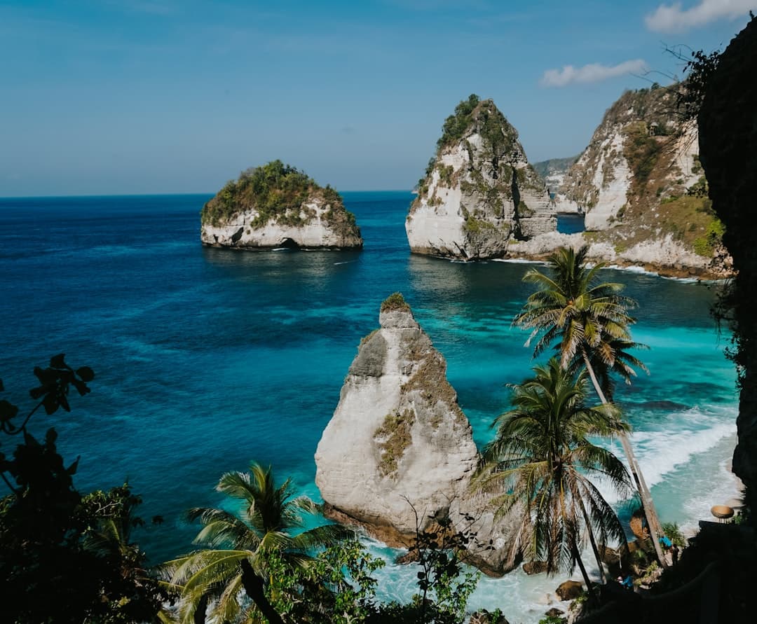 Tropical island cliffs with clear blue ocean water - Photo by Wahde Stock on Unsplash