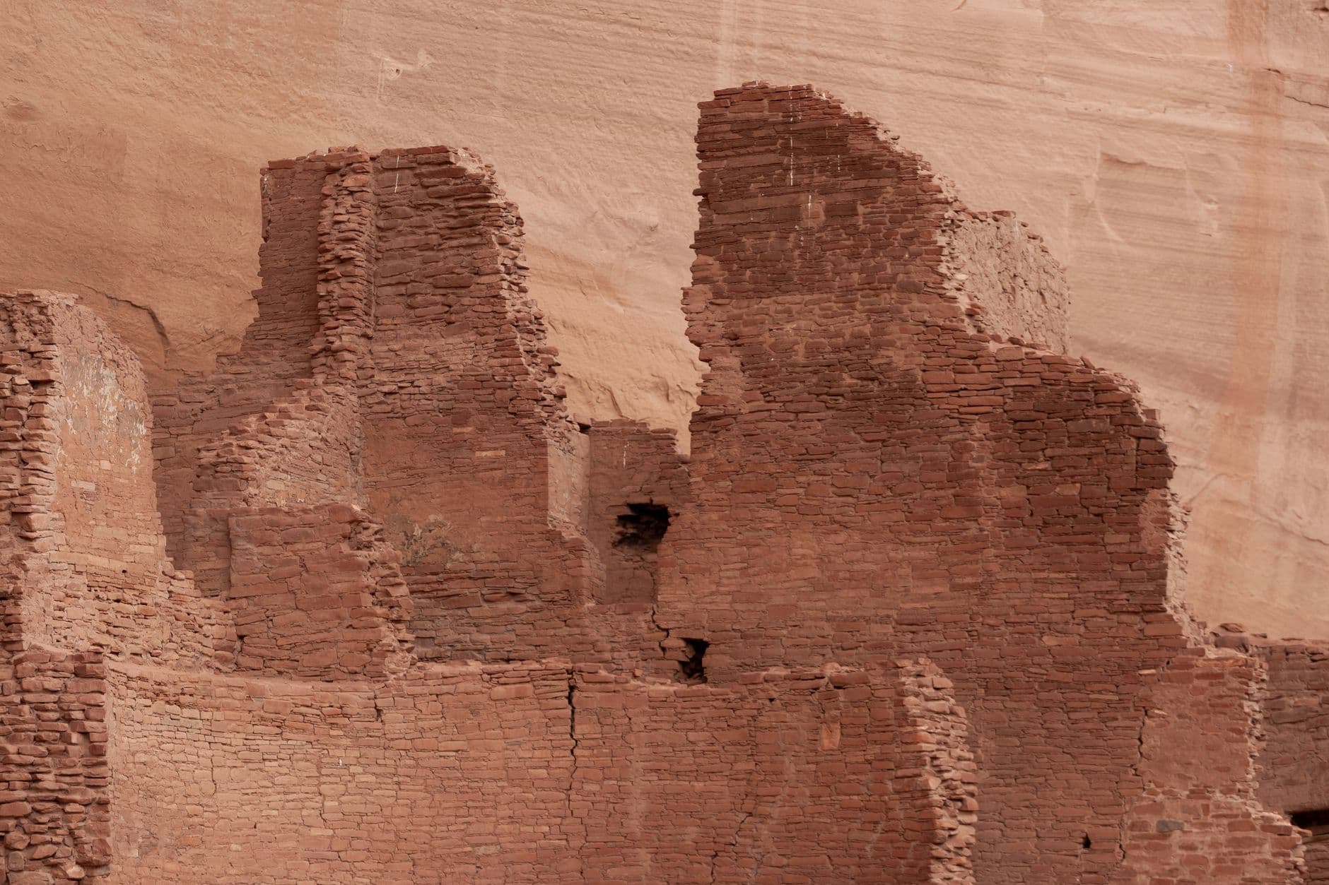 Ruined multi-story red sandstone structures built into a canyon wall, showing characteristic Ancestral Puebloan masonry and architectural design typical of Canyon de Chelly's cliff dwellings. - Photo by Jasper Tunney on Pexels