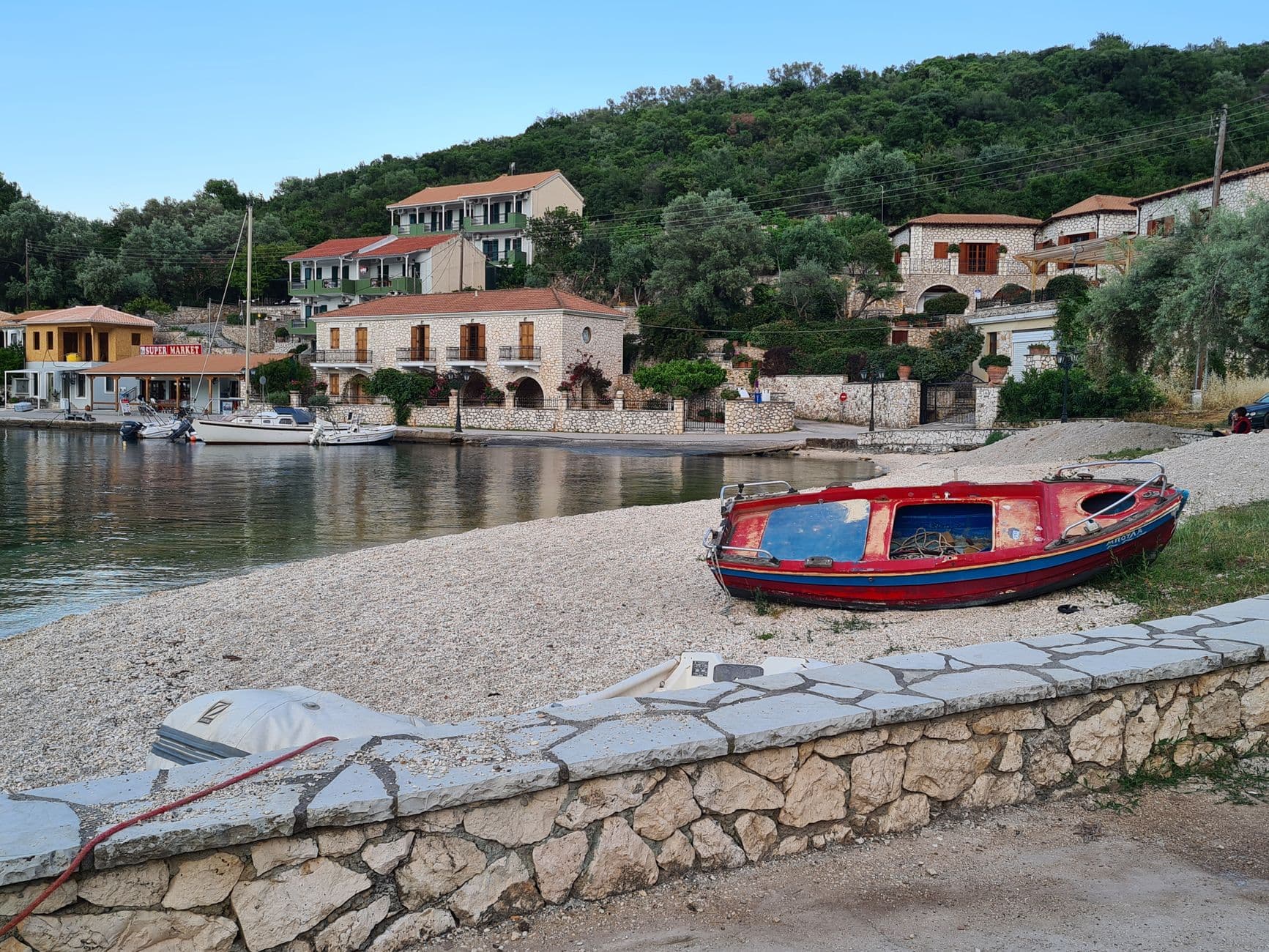 A peaceful off-season Mediterranean waterfront village with beached fishing boats, traditional stone buildings with red-tiled roofs, and lush hillside vegetation. - Photo by Michelle Chadwick on Pexels